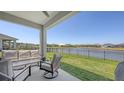 Covered patio with stylish seating, offering beautiful views of the expansive lawn and peaceful lake at 11869 Richmond Trl, Parrish, FL 34219