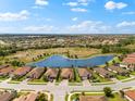 An aerial panorama showcasing the community's homes encircling a serene lake amidst a well-designed layout at 12501 Cinqueterre Dr, Venice, FL 34293
