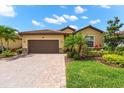 Lovely home featuring a brick-paved driveway, a two-car garage, and a well-manicured lawn with verdant foliage at 12501 Cinqueterre Dr, Venice, FL 34293