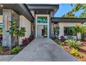 Elegant home entrance featuring a stone pathway and landscaped garden with exotic tropical plants at 1555 Eastbrook Dr, Sarasota, FL 34231