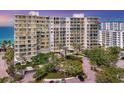Luxury beachfront condominium building featuring balconies, lush landscaping, and a circular driveway at 1800 Benjamin Franklin Dr # B310, Sarasota, FL 34236