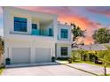 Contemporary white house with a balcony and a two-car garage, highlighted by a colorful sunset at 1842 Kenilworth St, Sarasota, FL 34231