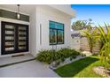 Modern home entryway featuring double doors, manicured landscaping, and a decorative sculpture at 1842 Kenilworth St, Sarasota, FL 34231