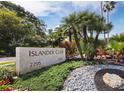 Stone community sign, Islander Club, surrounded by greenery and rocks, with palm trees and foliage in the background at 2301 Gulf Of Mexico Dr # 36N, Longboat Key, FL 34228
