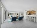 Inviting living room with tile floor, mirrored wall, bar seating area, and slider doors to a balcony with ocean views at 2301 Gulf Of Mexico Dr # 36N, Longboat Key, FL 34228