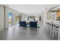 Bright living room with two blue chairs, a mirrored wall, tile flooring, and sliding glass doors leading to a balcony at 2301 Gulf Of Mexico Dr # 36N, Longboat Key, FL 34228