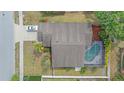 Aerial view of home with a screened pool, tropical trees and bushes, a large roof and a white car in the driveway at 4053 Lancaster Dr, Sarasota, FL 34241