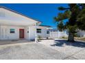 View of the home exterior showing a red front door, carport, fresh landscaping and fencing at 420 63Rd St # B East, Holmes Beach, FL 34217