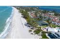 A stunning aerial view featuring beachfront condos and tennis courts along a beautiful, white sandy beach at 5055 Gulf Of Mexico Dr # 414, Longboat Key, FL 34228