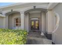 Covered home entrance featuring double doors, arched entry, and minimalist metal sculpture at 5554 Eastwind Dr, Sarasota, FL 34233