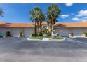 Condo exterior with garages, tile roof, palm trees, and neatly manicured landscaping at 7155 Boca Grove Pl # 102, Lakewood Ranch, FL 34202