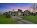 Charming single-story home with lush lawn and covered driveway under a pastel sunset sky at 80 Liles St, Terra Ceia, FL 34250