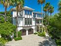 Elegant home with lush tropical landscaping and a brick driveway at 103 Park Ave, Anna Maria, FL 34216