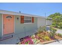 Charming home exterior showing peach door, wood shutters, landscaping, and a one-car garage at 130 E Seminole Dr, Venice, FL 34293