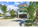 Modern home with a spacious driveway lined by palm trees leading to a 2-car garage and stylish entryway at 135 Grant Dr, Sarasota, FL 34236