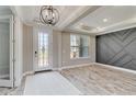 Bright foyer with a decorative front door, elegant chandelier, tray ceiling, and light wood-look floors at 14914 15Th E St, Parrish, FL 34219