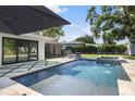 Sparkling in-ground pool with sun loungers, travertine patio, and well-manicured landscaping for outdoor enjoyment at 2202 Alpine Ave, Sarasota, FL 34239