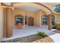 Inviting front entrance with warm colors, arched windows, and a charming porch with decorative stones and attractive chair at 3108 River Woods Dr, Parrish, FL 34219