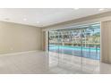 Bright living room with tile floors showcasing large sliding doors with a view of the screened-in pool at 3572 Ferndell, Sarasota, FL 34235