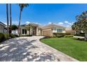 Beautiful front exterior of home with a brick driveway, well-manicured lawn, and lush landscaping at 8715 52Nd E Ave, Bradenton, FL 34211