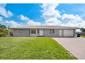 Charming single-story home with a gray exterior, brick driveway, and well-manicured lawn at 9080 Caloosa Dr, Venice, FL 34293