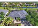 Stunning aerial view of a luxury home with a tile roof situated on a waterfront property with lush greenery at 10411 Winding Stream Way, Bradenton, FL 34212