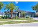 Charming home features a well-manicured lawn, lush landscaping, and a stately palm tree, all enhancing its curb appeal at 10411 Winding Stream Way, Bradenton, FL 34212
