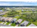 Aerial view of a neighborhood featuring homes surrounding ponds and lush green spaces under a blue sky at 14265 17Th E Ct, Parrish, FL 34219