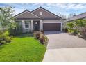 Attractive single-story home with lush green lawn, brick driveway, and well-maintained landscaping at 14265 17Th E Ct, Parrish, FL 34219