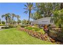 Well-maintained community entrance sign with vibrant landscaping and mature palm trees at 1520 Dorgali Dr, Sarasota, FL 34238