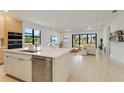 Open concept kitchen with an island that flows into the living room with large windows at 18525 Midsummer Pl, Venice, FL 34293