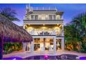 Stunning backyard oasis with pool, spa, covered patio, white rocking chairs, and lush tropical landscaping at 221 Grant Dr, Sarasota, FL 34236