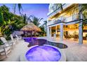 Backyard featuring a custom pool and spa with tiki umbrella surrounded by lush tropical landscaping and white lounge chairs at 221 Grant Dr, Sarasota, FL 34236