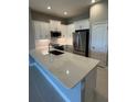Modern kitchen featuring white cabinets, stainless steel appliances, and a spacious island with stone countertops at 24835 Buckingham Way, Port Charlotte, FL 33980