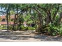Exterior view of a home surrounded by lush greenery and trees in a neighborhood with private streets at 3500 El Conquistador Pkwy # 117, Bradenton, FL 34210