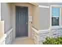 Close-up of a gray front door with stone accents and a welcoming 'Welcome' sign at 3813 Lively Coral Pl, Bradenton, FL 34208