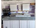 Partially renovated kitchen with white cabinets, granite countertops, and stainless steel appliances at 4444 Swift Rd # 34, Sarasota, FL 34231
