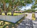 A single-story home with large trees and a long driveway behind a white fence at 5024 37Th E St, Bradenton, FL 34203