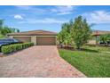 Brick paver driveway leading to a 3 car garage with a neatly manicured lawn and tropical landscaping at 6642 Willowshire Way, Bradenton, FL 34212