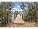 A wooden dock extends into the water, framed by trees and shrubs and the hint of houses across the canal at 891 Palmetto Ne Dr, Port Charlotte, FL 33952
