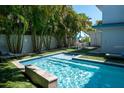 Inviting backyard pool with a waterfall feature, surrounded by lush greenery and an umbrella table set at 91 Avenida Veneccia, Sarasota, FL 34242