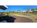 Spacious backyard featuring a grassy area, newly planted trees, mulch beds, and a fence-lined perimeter at 9176 Tequila Sunrise Dr, Sarasota, FL 34241