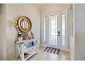 Bright entryway featuring a decorative table with an ornate mirror and a beautiful glass-paneled front door at 20655 Valprato Ct, Venice, FL 34293