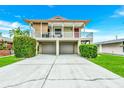 Charming two-story home featuring a covered balcony, two-car garage, and well-manicured lawn at 216 Palmetto Ave, Anna Maria, FL 34216