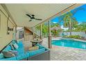 Inviting outdoor space with a covered patio, fan, outdoor kitchen, lush greenery, and refreshing swimming pool at 216 Palmetto Ave, Anna Maria, FL 34216