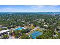Expansive aerial view of community amenities: pool, tennis courts, and ample green space in wooded setting at 2483 Bay St, Sarasota, FL 34237