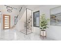 Bright foyer featuring marble floors, a glass-enclosed wine rack, and modern staircase at 2483 Bay St, Sarasota, FL 34237