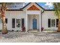 Close-up of a charming home's entrance, featuring a blue door, black shutters, and lush landscaping at 305 73Rd St, Holmes Beach, FL 34217