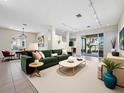 Bright living room featuring an open floor plan, neutral walls and flooring and a large green couch with decorative pillows at 3835 Alamanda Dr, Sarasota, FL 34238
