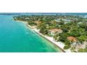 Aerial view of a luxury waterfront home with private beach access surrounded by lush greenery at 4050 Higel Ave, Sarasota, FL 34242